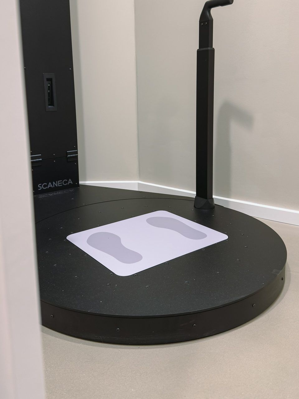 Round platform of the 3D body scanner with footprints, behind it the handle