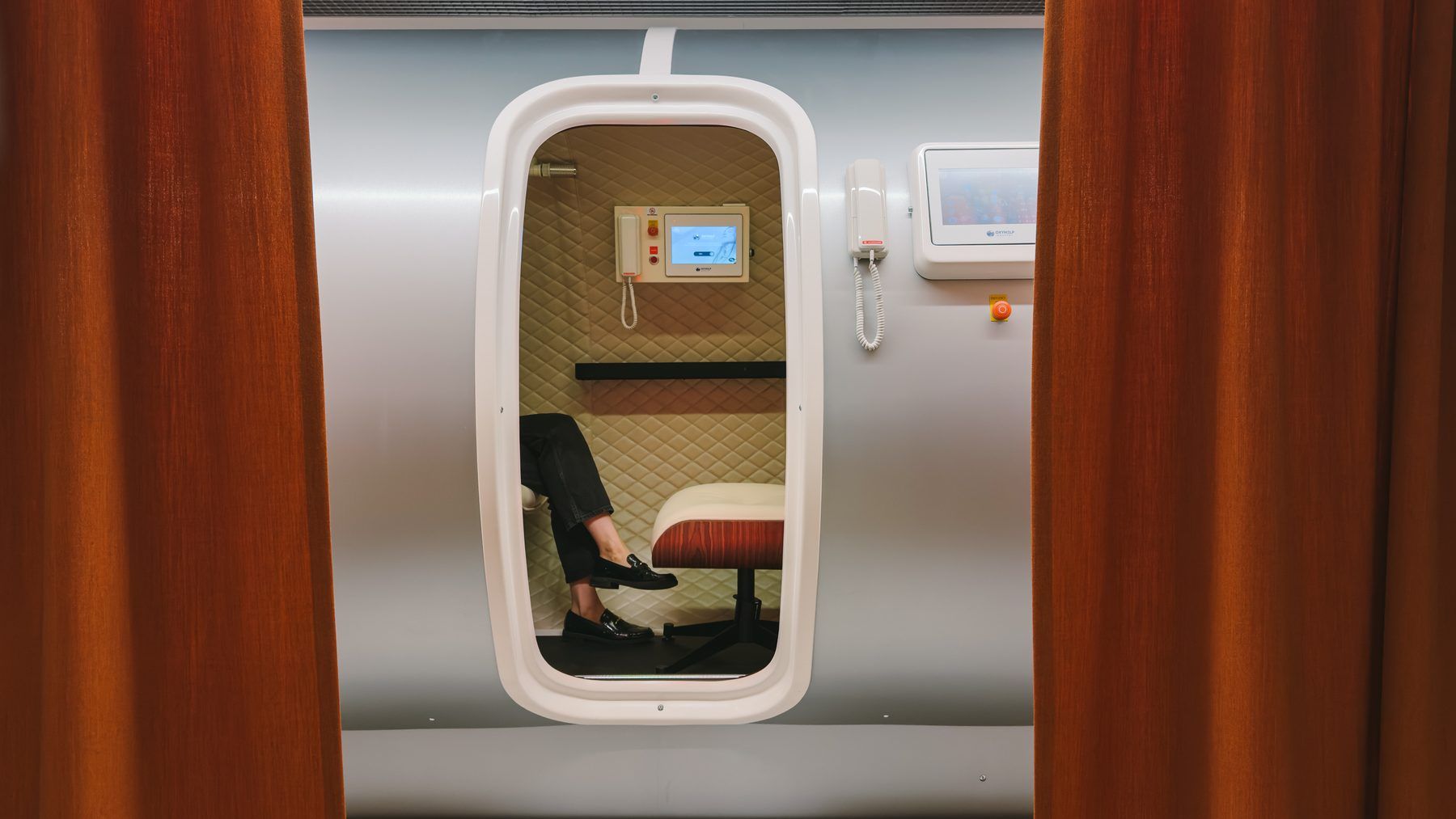 Walk-in chamber for hyperbaric oxygen therapy, framed by rust curtains