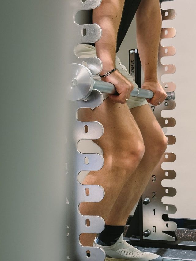 Hands pulling on a fixed bar at the rack, knees bent