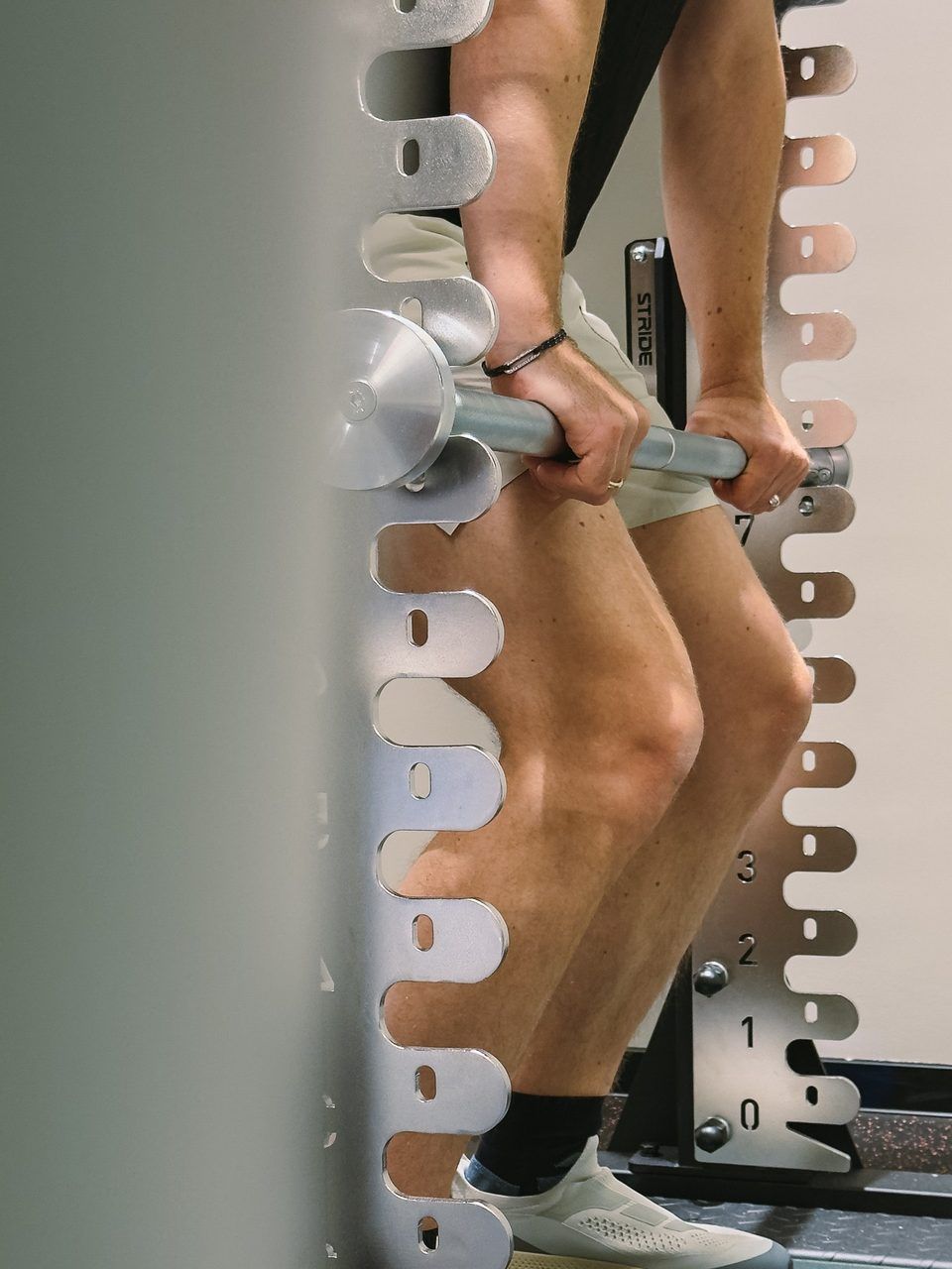 Hands pulling on a fixed bar at the rack, knees bent