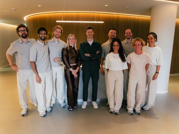 THE WELL team, most in light uniforms, in front of a wooden wall